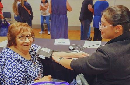 Image of a person checking an elderly person's blood pressure